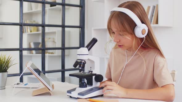 Teen Girl Using Microscope for Research While Online Education at Home