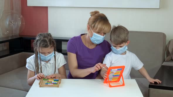 Mother Teaches Children in Medical Masks To Count on the Bills in the Room. Social Distancing and