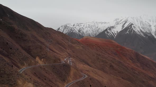Panoramic Aerial View of Curved Road on Mountain Pass with Large Trucks Passing Along It Against alt
