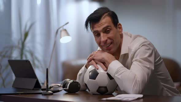 Portrait of Smiling Middle Eastern Man Sitting in Home Office with Face of Sports Ball Looking at alt