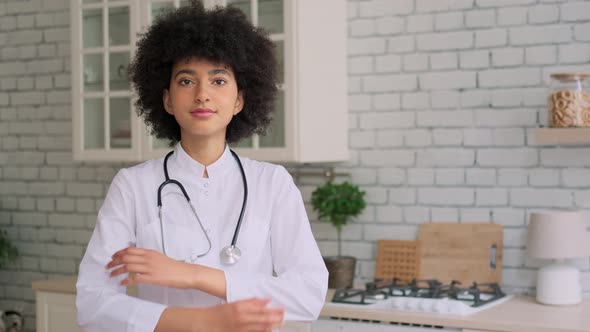 Portrait of Afro American Woman Doctor in Robe Looking at Camera and Crossing Her Arms alt