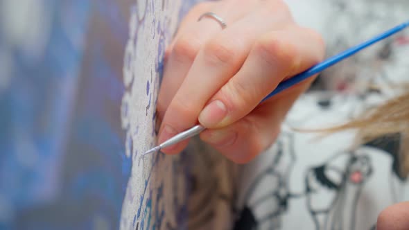 Woman Hand Holds a Brush and Paints with Paint Painting on an Easel Draws the Details of the Picture alt