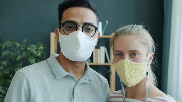 Portrait of Young Mixed Race Couple Girl and Guy in Reusable Medical Masks at Home alt