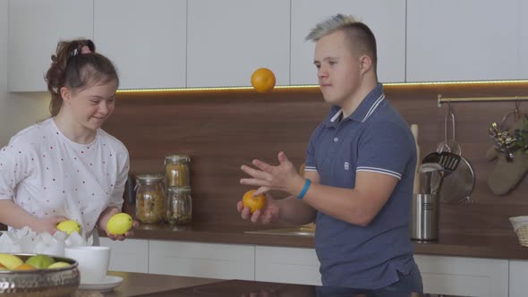 Young Couple with Down Syndrome Juggle at Kitchen