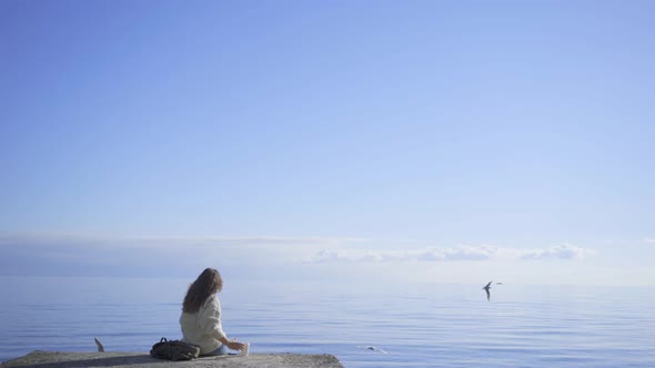 Woman Drinks Coffee Sitting on Sea Pier