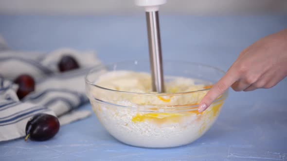 A housewife whips cottage cheese and chicken eggs with a blender.