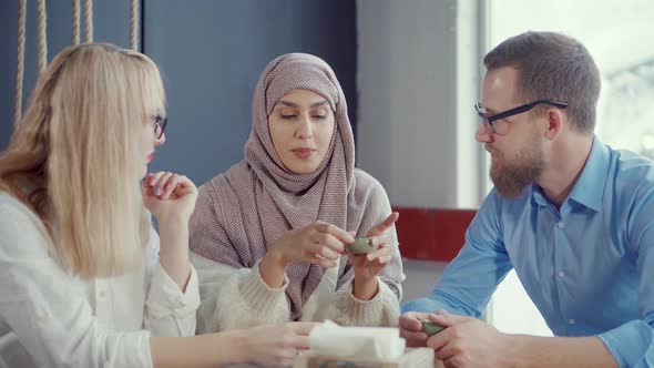 Muslim Woman Is Speaking Stories To Her Male and Female Friends in Cafe alt