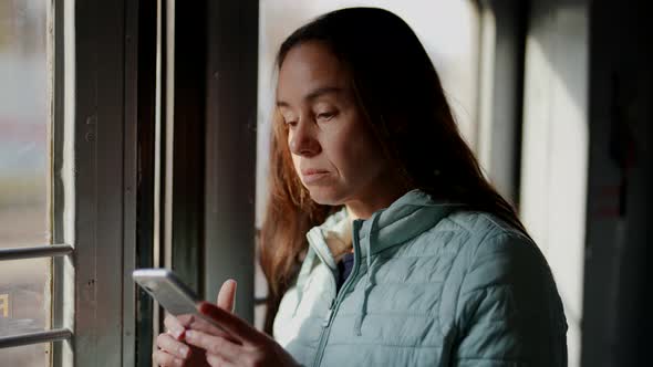 City Dweller Woman is Using Suburban Train for Travelling to Work Using Smartphone alt