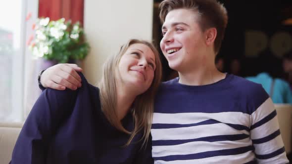 Young Couple Sitting at the Table in Cafe Embracing Each Other alt