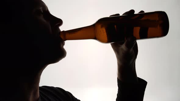 The Silhouette of Male head drinking from a brown bottle