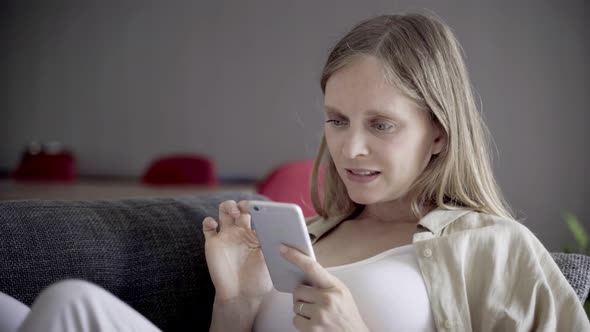 Focused Beautiful Young Woman Using Smartphone at Home alt