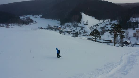 Aerial View of a Snowboard Going Uphill Near the Village at Sunset alt