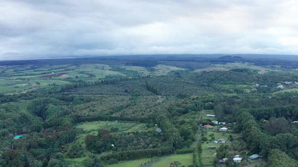 Wide aerial dolly shot of rural rainforest and farmland on the Big Island of Hawaii. 4K alt