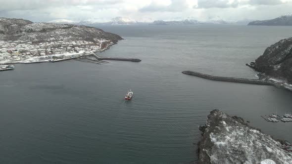 Boat leaves Skjervoy harbor heading towards fishing grounds in the Arctic, drone alt
