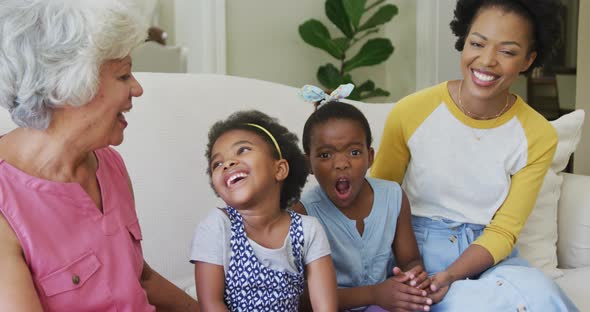 Portrait of happy african american grandmother with adult daughter and granddaughters in living room alt