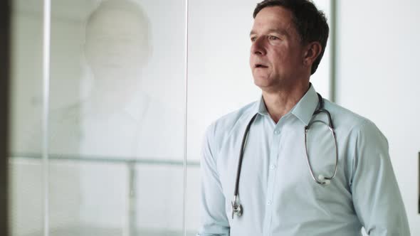 Mature Adult Male Doctor in Hospital looking out of window