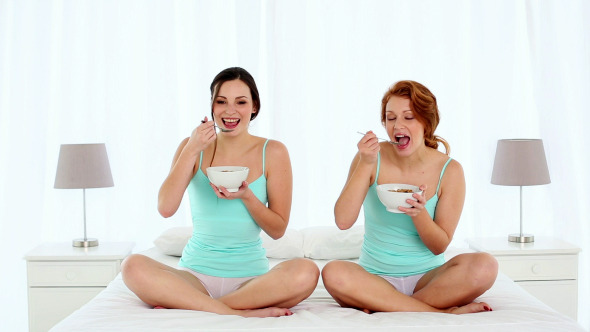 Cute Women Eating Cereal While Sitting On Bed