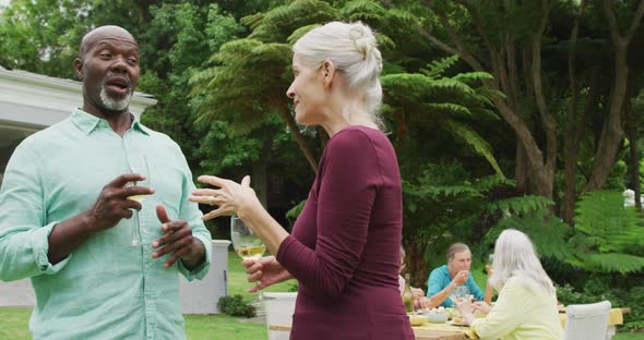 Animation of diverse happy senior female and male friends talking in garden alt