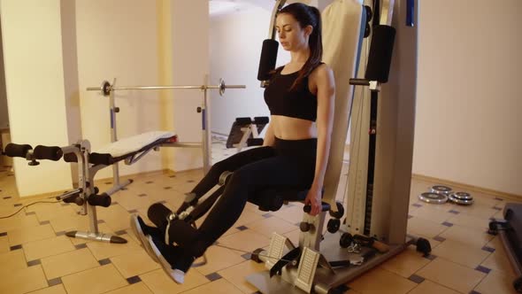 Wide Shot of Concentrated Gorgeous Slender Sportswoman Training Leg Muscles Using Exercise Machine alt