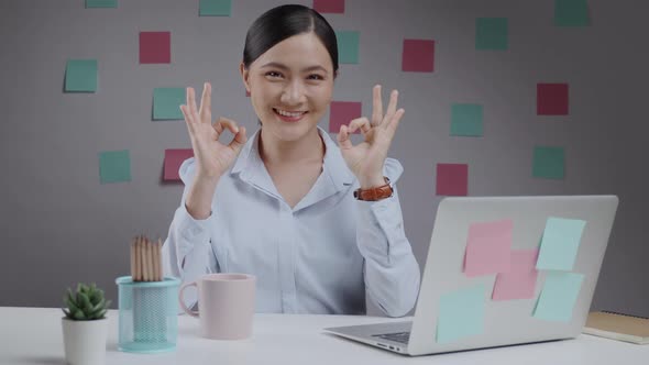 Asian woman happy working looking at camera and showing OK sign.