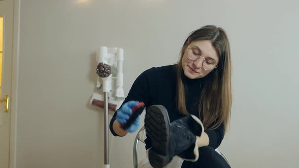 A Beautiful Young Woman Brushes Her Shoes Before Going to Work