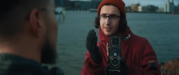Young man with glasses giving directions to model while he takes shots with vintage camera alt