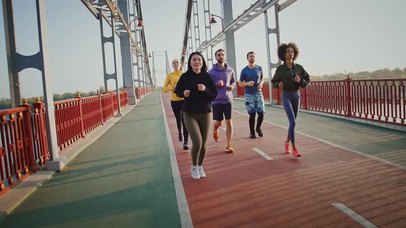 Sporty Friends Practicing Morning Jog on Sports Bridge in City Slow Motion alt