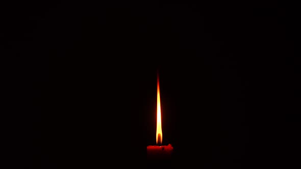 A burning candle with a dark background.