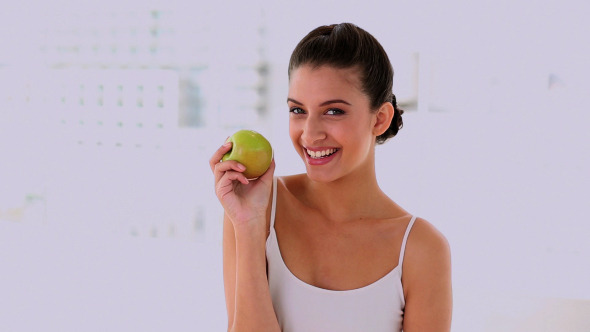 Amused Beautiful Woman Smelling And Showing Apple