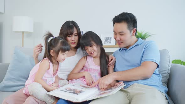 Asian family looking at photographs on old picture album recalls the past. alt