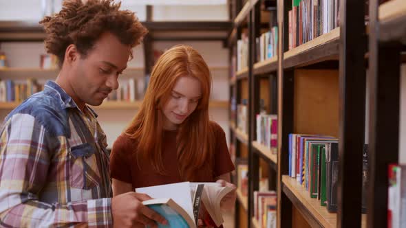 Beautiful Teenage Foxy Girl in Library Discussing Books with African American Guy with Afro Haircut alt