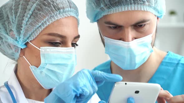 Team of Doctors in Masks Discuss Patients Diagnosis on Tablet in Clinic alt