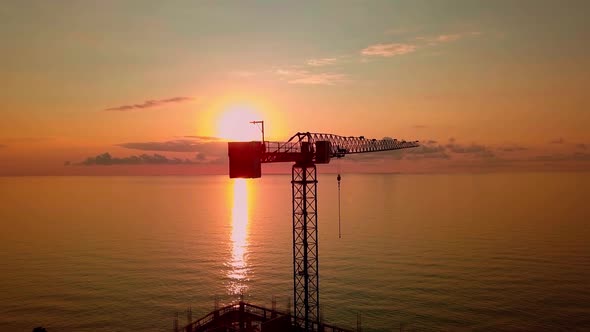 crane at sunset from a bird's-eye view, sun's rays pass through crane structure. alt
