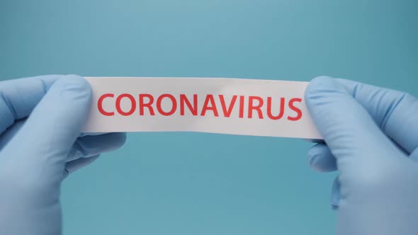 Coronavirus Background, Hands in Medical Gloves Hold a Piece of Paper with Coronavirus Printed on It alt
