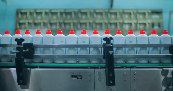 Bottles of White Plastic Bottles Moving Along a Conveyor Belt alt