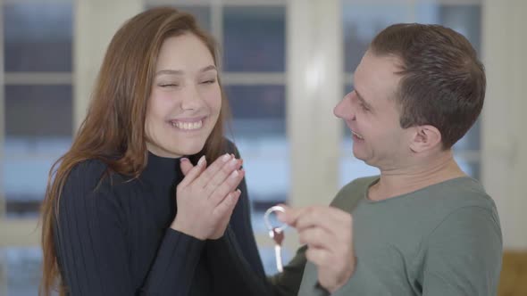 Portrait of a Happy Married Couple Showing the Keys of a Purchased New House or Apartment alt