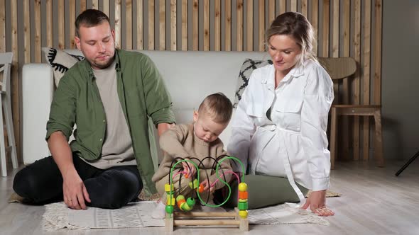 Little Boy Plays with Puzzle Game Sitting Near Parents alt