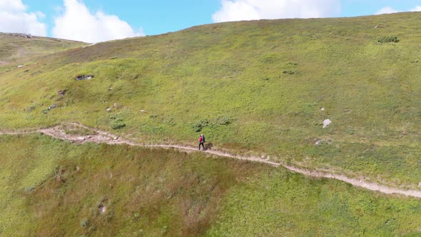 Aerial View of a Traveler with Backpack Climbing Along Mountain Slope. Epic Shot alt