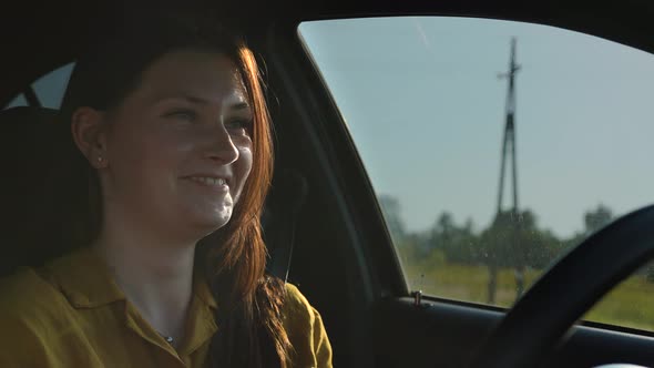 Women with Red Hair in a Yellow Shirt Drives a Car Happy Smiling