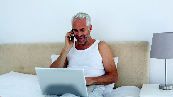 Laughing Man Using Laptop While On The Phone