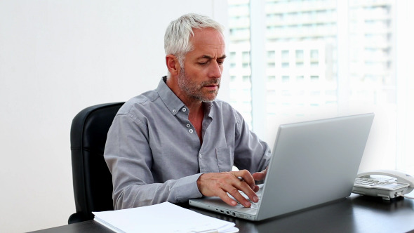 Casual Businessman Working On Laptop At Desk
