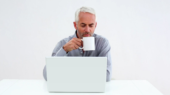 Casual Businessman Working On Laptop And Drinking alt