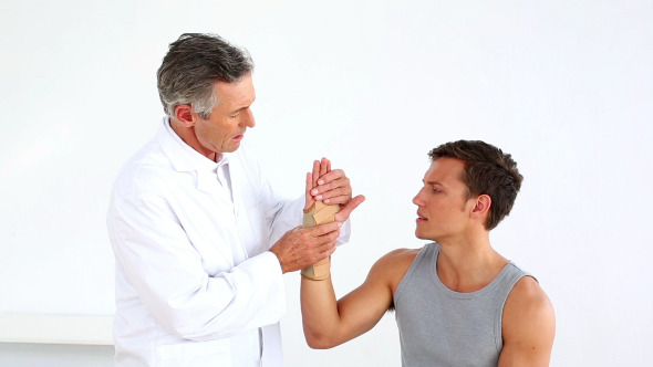 Mature Doctor Checking Sportsmans Injured Wrist
