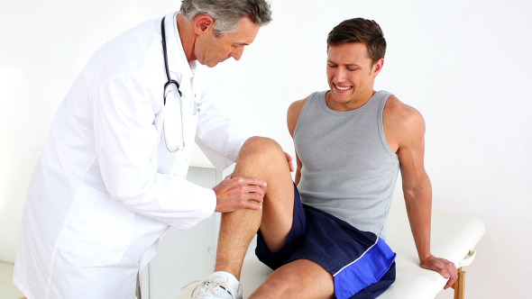 Mature Doctor Checking Sportsmans Injured Knee