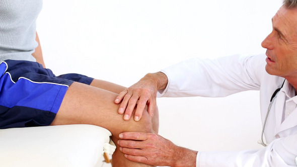 Mature Doctor Touching Sportsmans Injured Knee