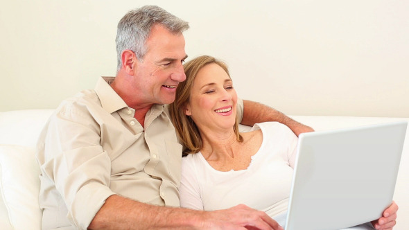 Mature Couple Using Laptop Together On The Couch