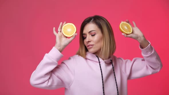 Woman in Casual Pink Clothes Holding Oranges and Dancing