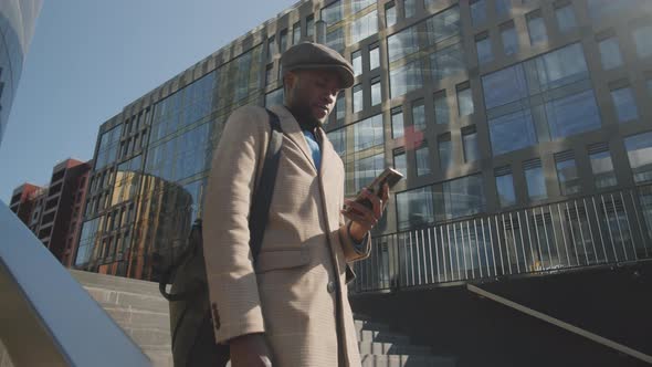 Afro-American Businessman Walking in City and Using Smartphone alt
