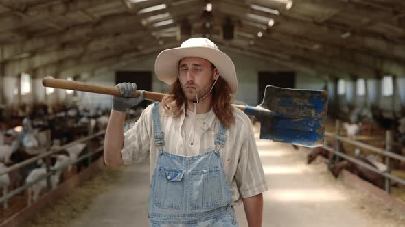 Man Holding Shovel on Shoulder While Walking at Goat Farm alt