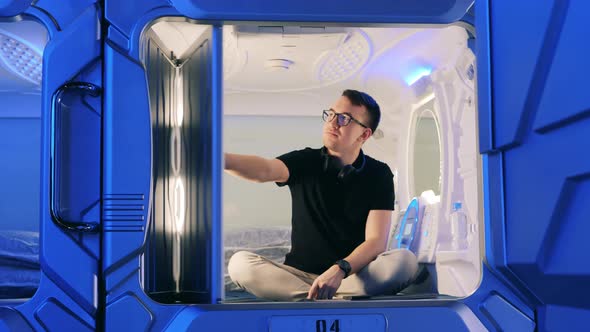 A Man Opens a Door of a Capsule Hotel Room From Inside alt